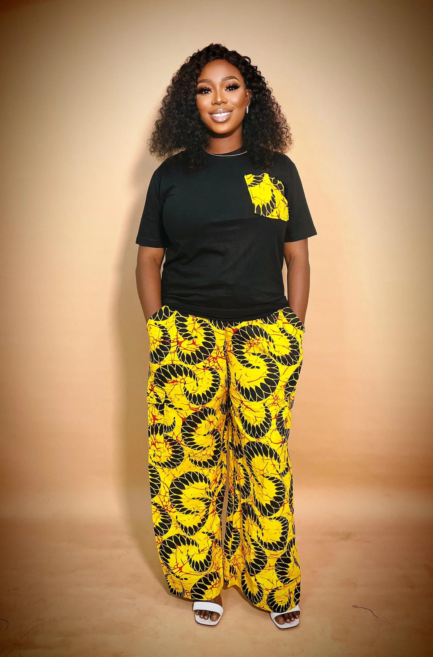 Woman wearing our African Print 2 Piece Set yellow patterned pants on a beige background