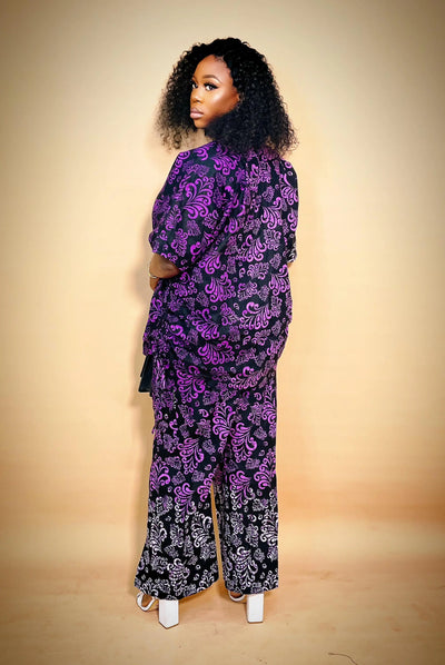 Lady wearing a black and purple patterned African Two Piece Set  against a beige background