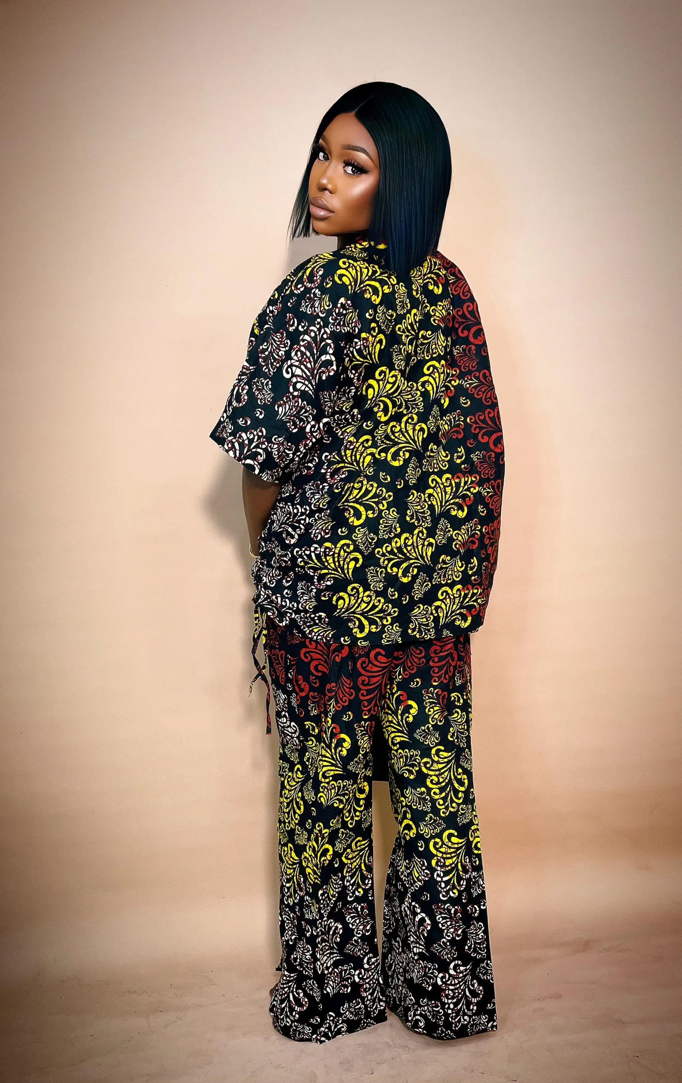 Woman wearing a colorful patterned African Two Piece Set against a beige background