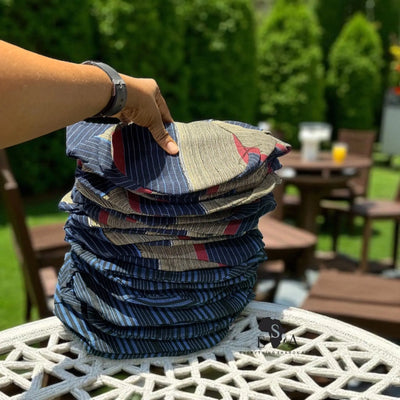 Stack of patterned Asooke Cap for men held by a person outdoors 