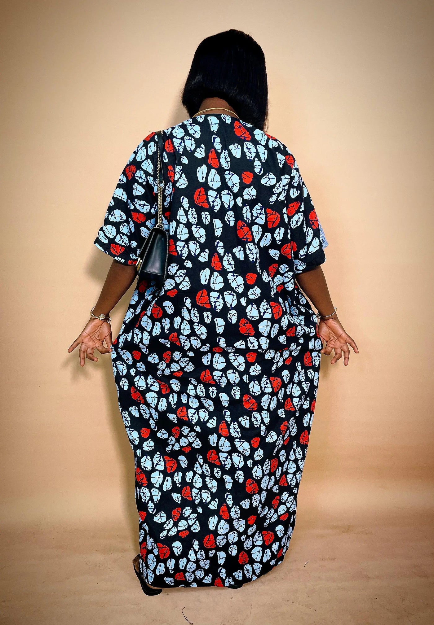 Back view of Woman wearing a long Ankara dress with net Lace with a plain background
