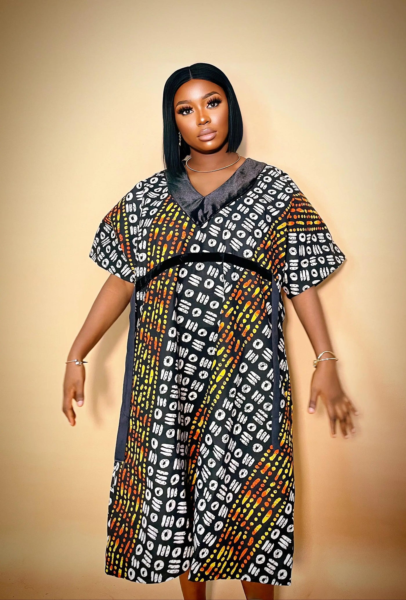 Beautiful woman wearing a colorful Luxury Ankara Velvet Gown against a beige background 
