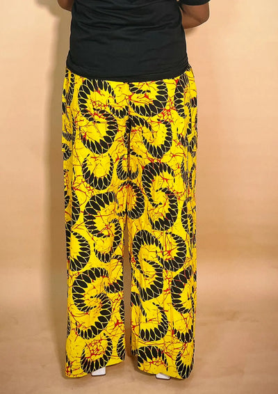 Front view of a yellow patterned Ankara baggy pant with gold chain detail on a blurred background
