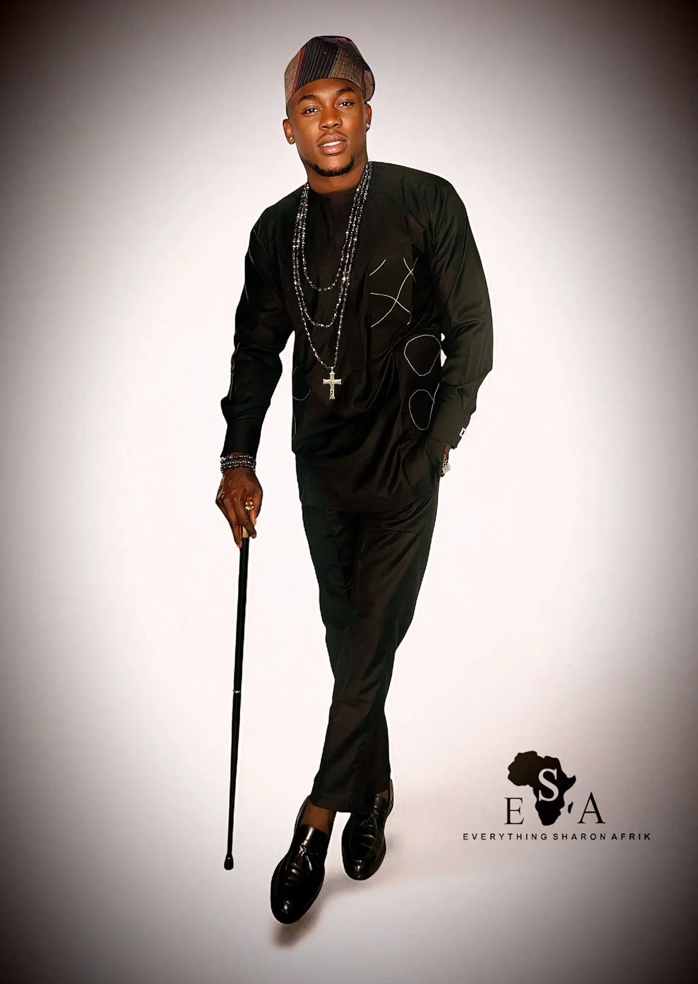 Man in black African Senator Long Sleeve Set with a cane on a gray background, featuring the brand 'E S A'.