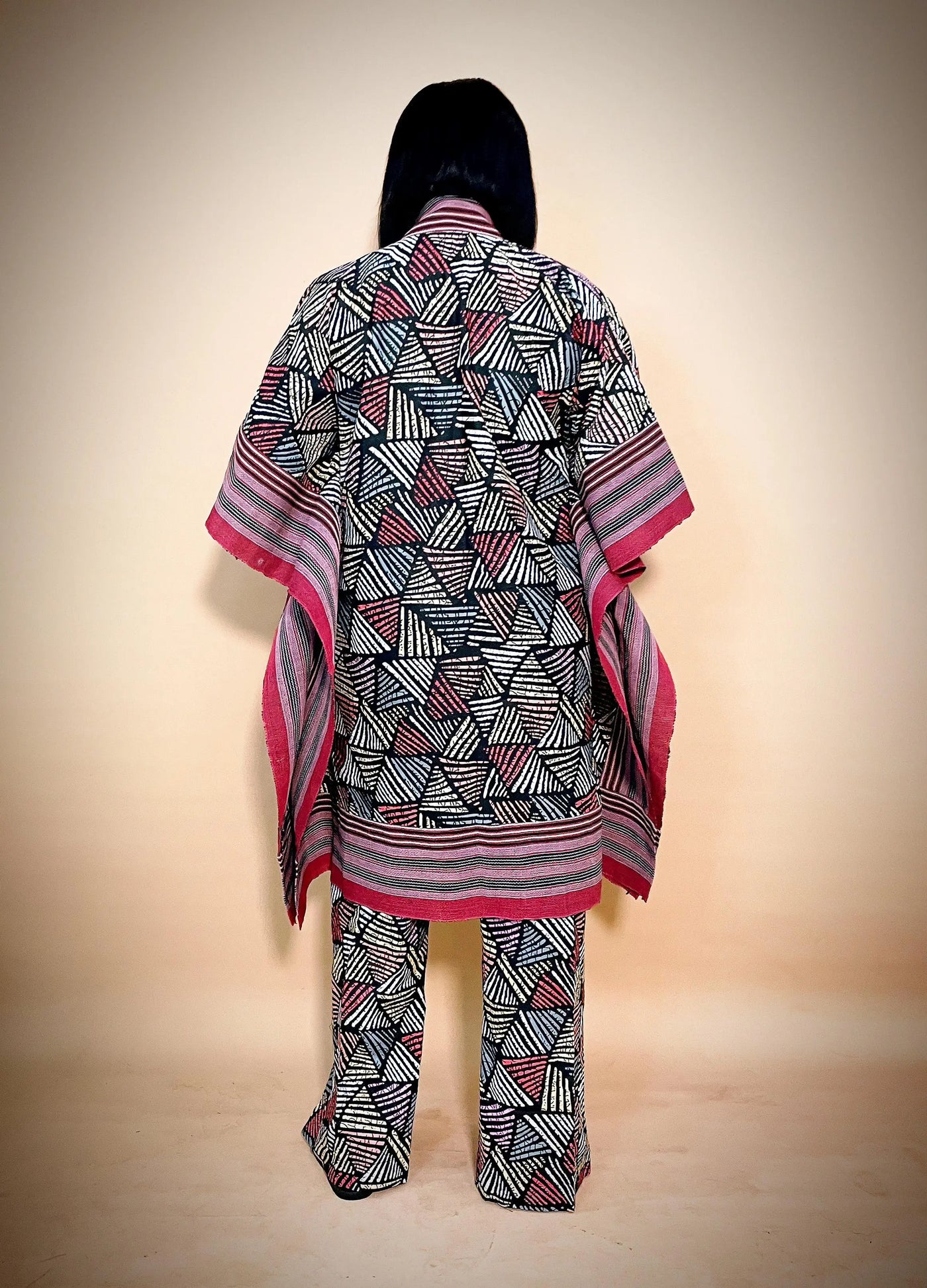 Person wearing a patterned outfit with a matching shawl on a beige background