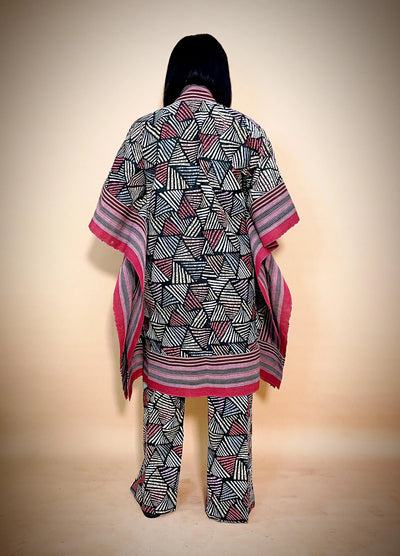 Person wearing a patterned outfit with a matching shawl on a beige background