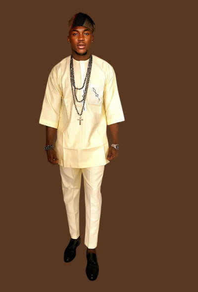 Man wearing an African Senator Wear for Men with multiple necklaces on a brown background