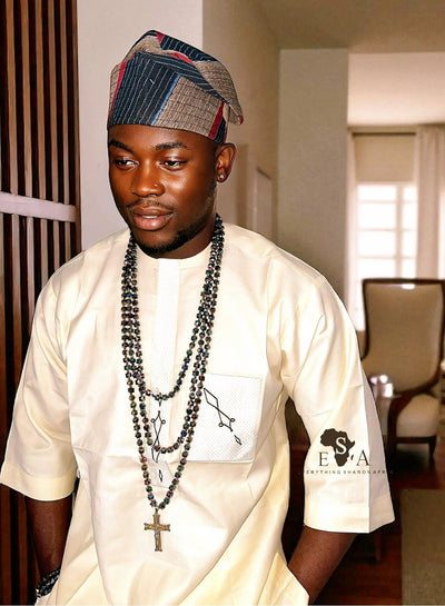 Man wearing a traditional Asooke cap for men with a white attire in an indoor setting
