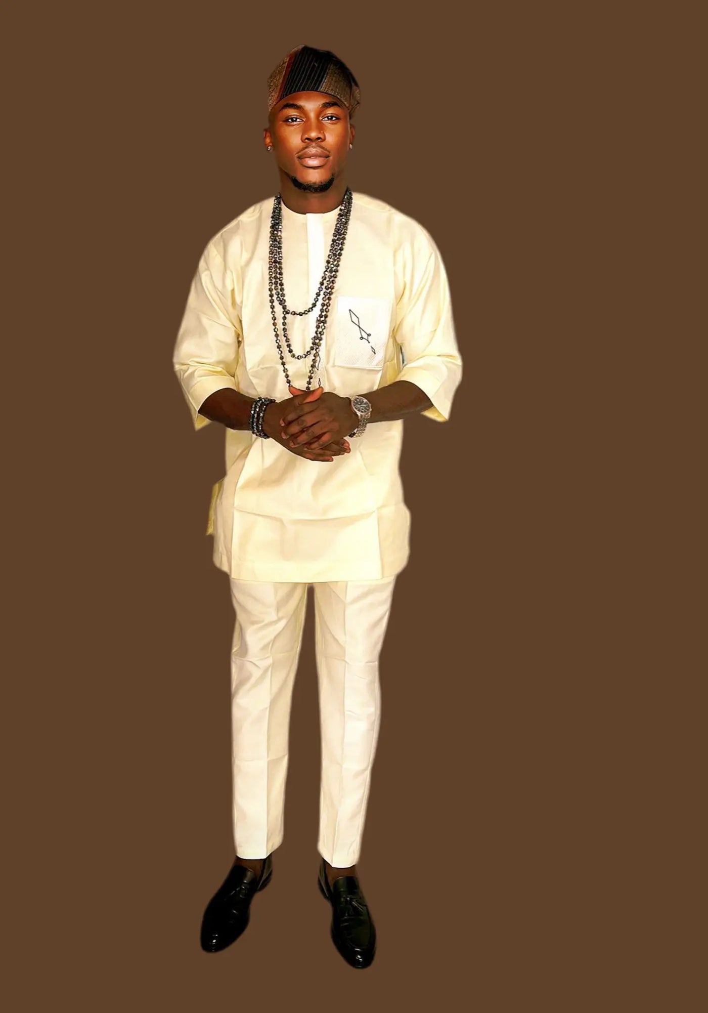 Man wearing a traditional African Senator Wear for Men outfit with a plain background