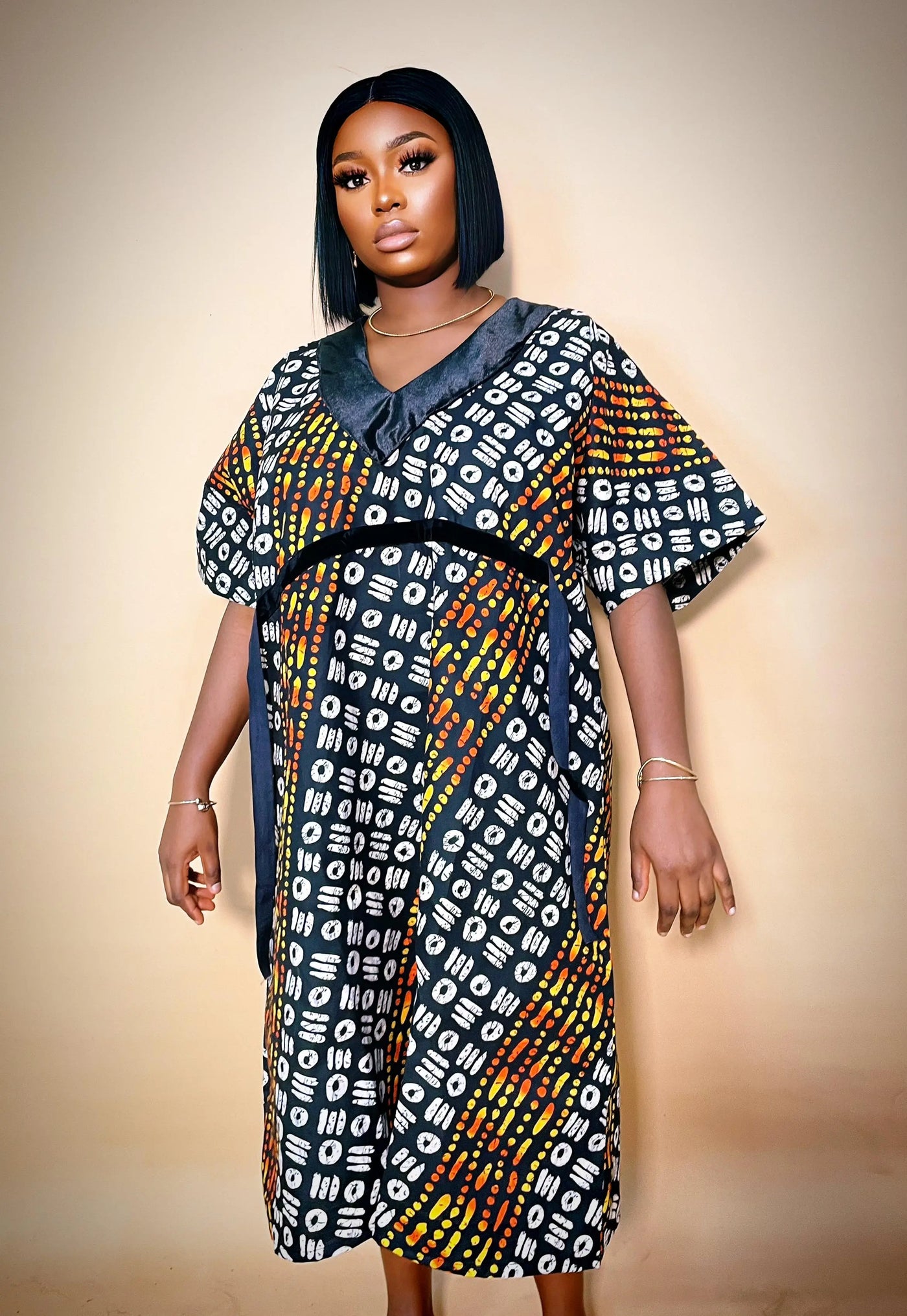 Woman wearing a colorful Luxury Ankara Velvet Gown against a beige background