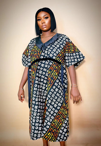 Woman wearing a colorful Luxury Ankara Velvet Gown against a beige background