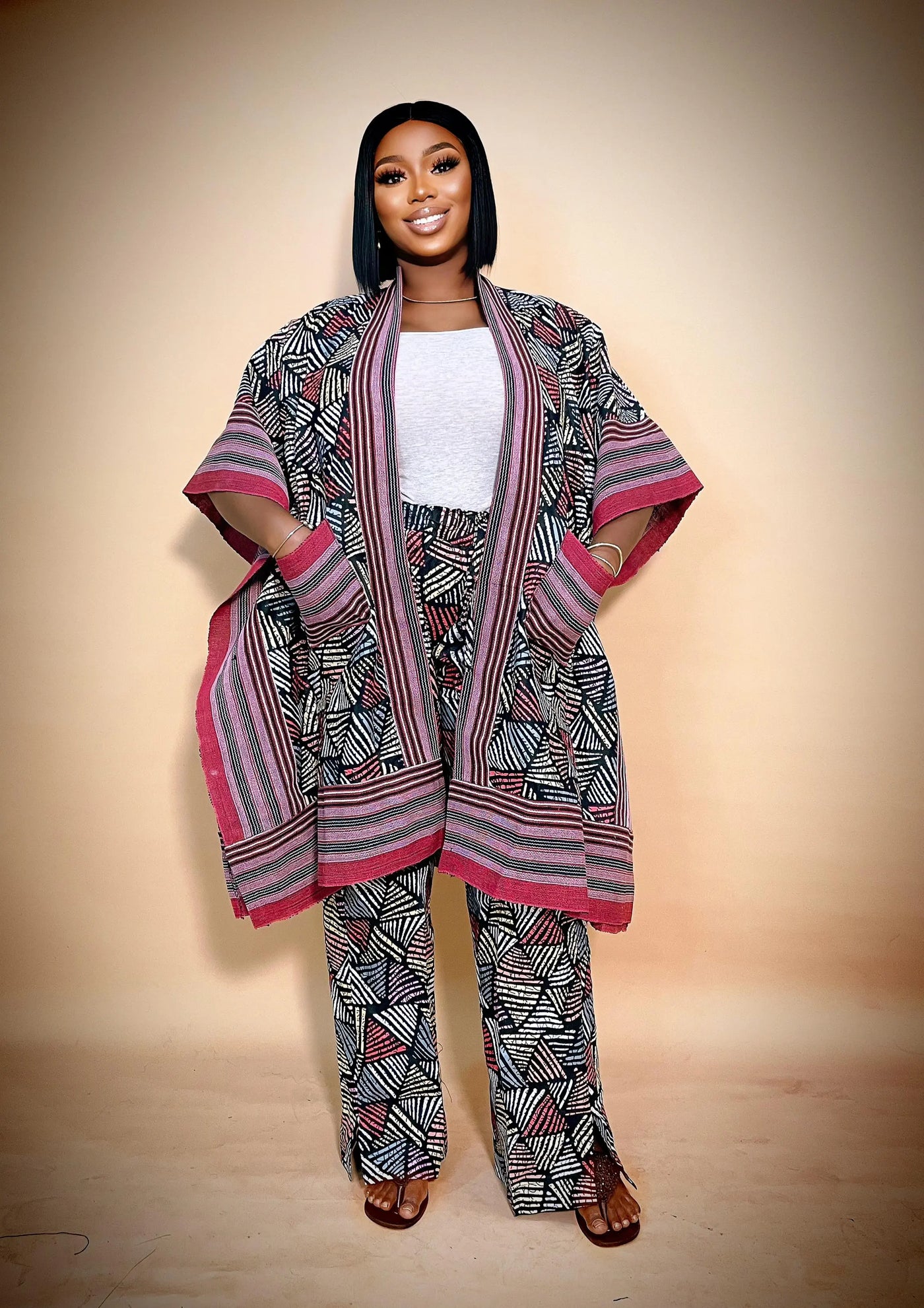 Woman wearing a patterned outfit with a matching shawl against a beige background