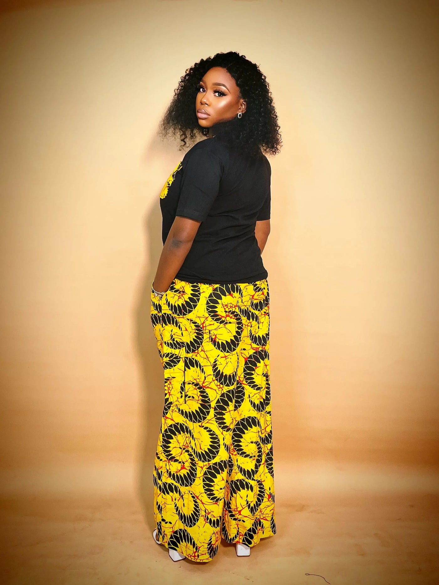 Woman wearing our African Print 2 Piece Set yellow patterned pants on a beige background