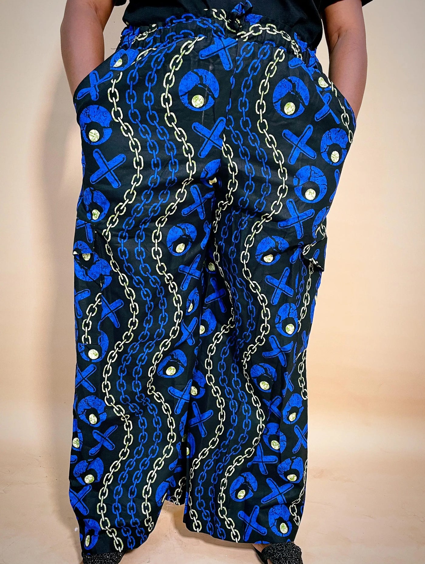 Front view of a blue patterned Ankara baggy pant with gold chain detail on a blurred background