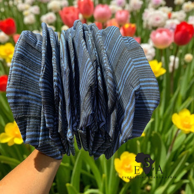 Stack of blue striped Asooke cap for men against a colorful tulip background