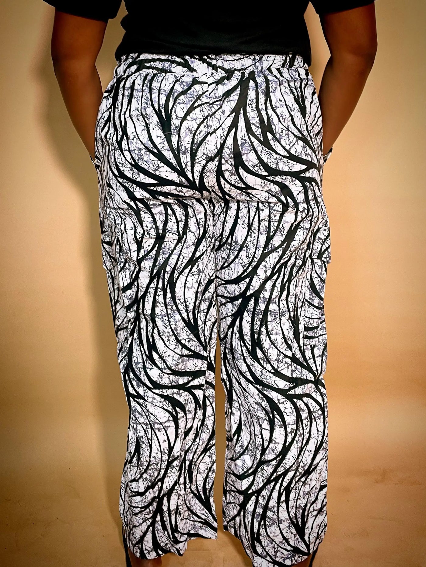 Back view of a black and white patterned Ankara baggy pant with gold chain detail on a blurred background