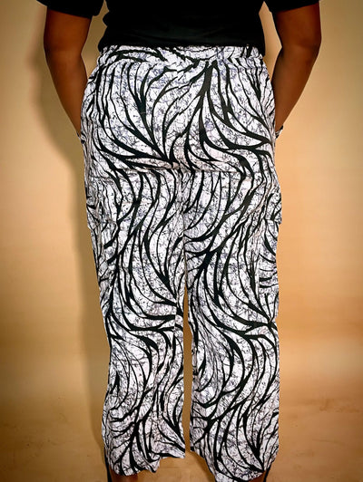 Back view of a black and white patterned Ankara baggy pant with gold chain detail on a blurred background